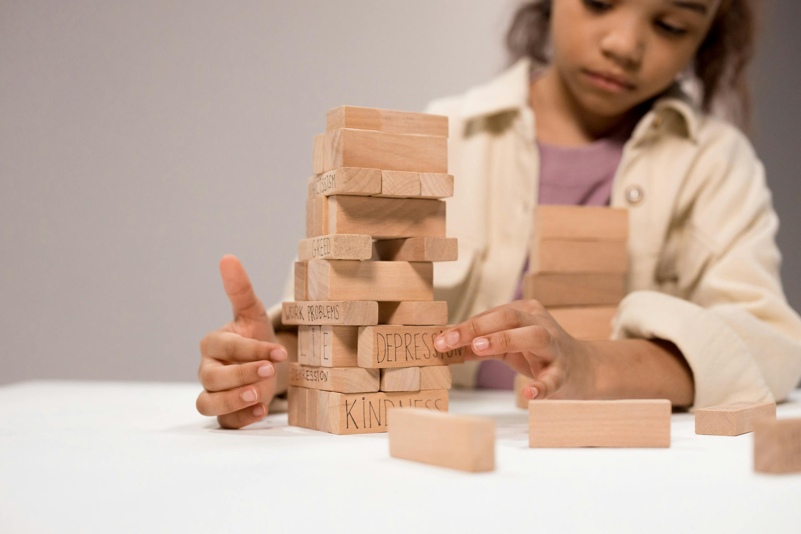 a-child-thoughtfully-stacks-wooden-blocks-with-words-like-depression-and-kindness.-9196728-scaled
